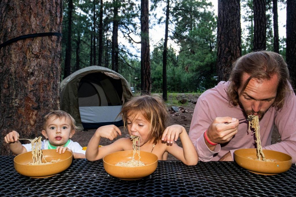 Father and children enjoying a meal at a campground picnic table
