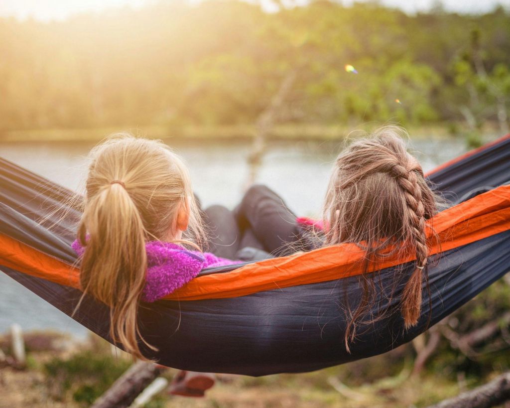 Two girls sharing a hammock while camping
