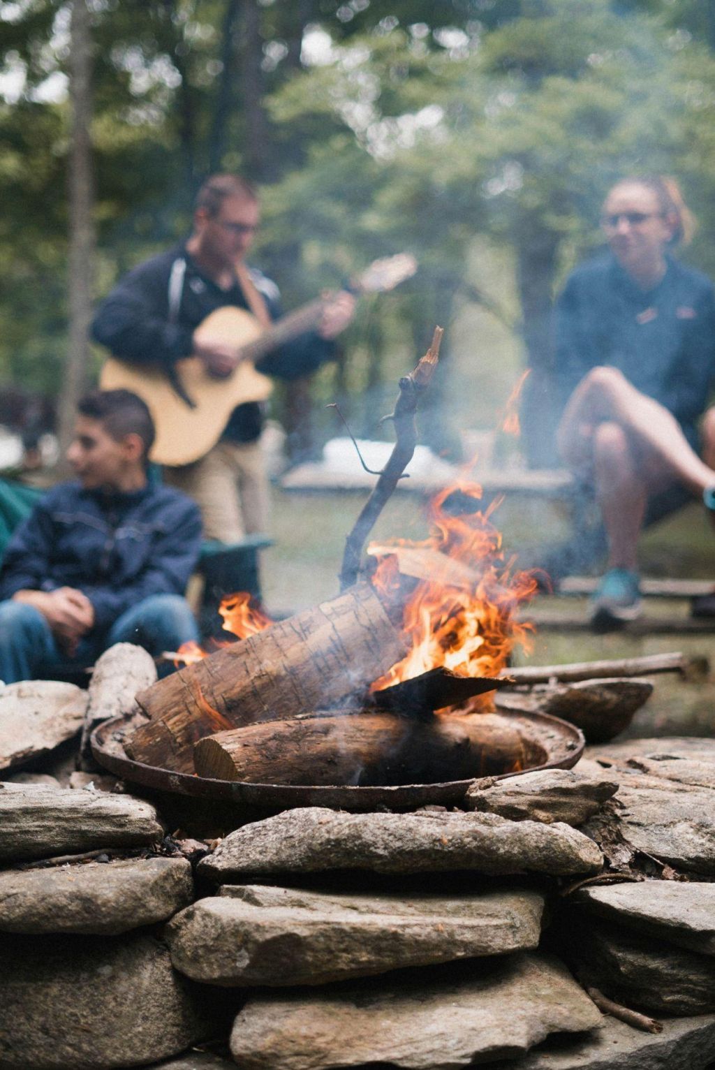Friends hanging out around a campground fire ring